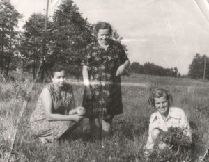 Na tym czarnobiałym zdjęciu widzimy trzy kobiety. Dwie kucają, jedna trzyma w rękach bukiet polnych kwiatów. Heronima Dzierma (pierwsza z prawej strony) z mamą Franciszką i siostrą Eugenią, po powrocie do Polski.