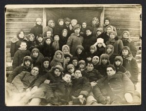 Fotografia przedstawia grupę kilkudziesięciu osób ubranych w zimowe stroje. Część z nich leży na ziemi, pozostali stoją, jedni za drugimi.