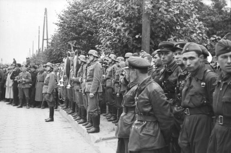 Fotografia przedstawia grupę osób w mundurach stojących na ulicy