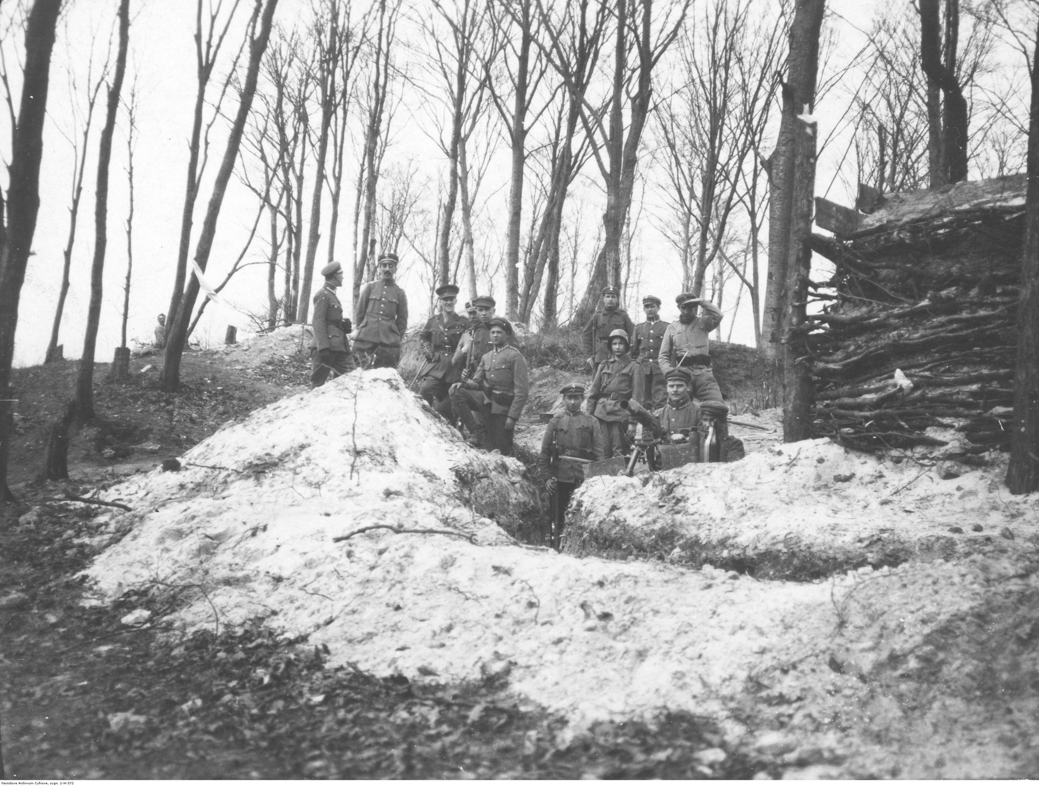 Grupa żołnierzy pozujących do zdjęcia w okopie na tle drzew