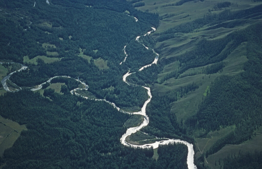 Na zdjęciu widać dolinę rzeki otoczonej wzgórzami porośniętymi drzewami.