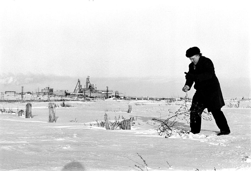 Na zdjęciu widać mężczyznę wyciągającego ze śniegu drut kolczasty.