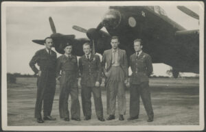 Czterech mężczyzn w mundurach i jeden w garniturze, stojący przed samolotem śmigłowym