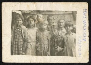 A group of kids standing by the wooden house