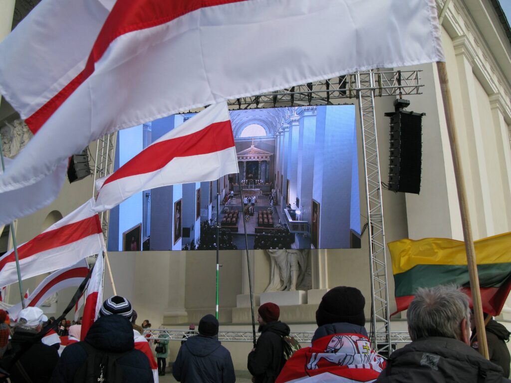 Fotografia przedstawiająca osoby machające flagami w kolorach biało-czerwono-białym