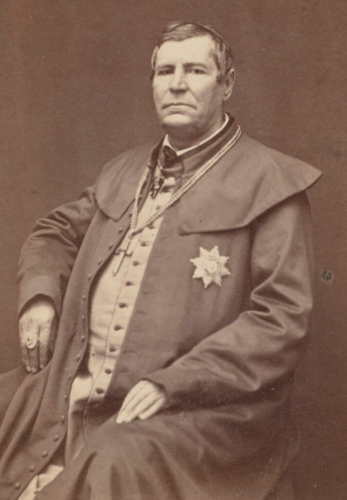 Portret fotograficzny duchownego z krzyżem na piersi i orderem w kształcie gwiazdy.